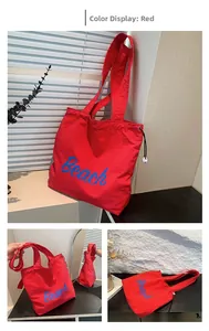 Detail of red beach tote bag with blue Beach text, drawstring closure and shoulder strap