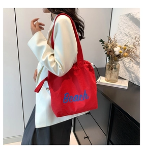 Detail of red canvas tote bag with blue Beach print and white drawstring closure