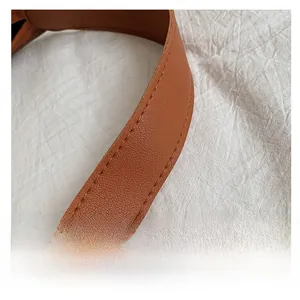Close-up of brown lychee grain leather handle with reinforced stitching on tote bag