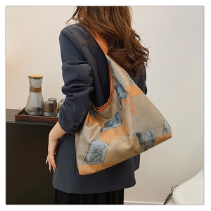 Detailed view of large color-block tote bag made of soft leather on a model's shoulder