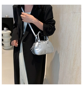 Silver metallic mini Boston bag shown worn crossbody over a stylish black coat