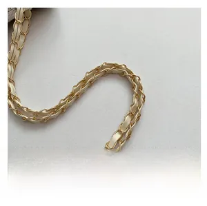 Detailaufnahme der hellgoldenen Metallkette mit eingeflochtenem cremeweißem Leder