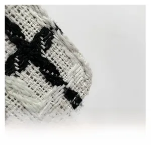 Nahaufnahme der schwarz-weißen Tweed-Stofftextur einer modischen Ketten-Quadrat-Tasche