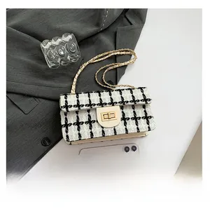 Detailansicht der Mini-Tweed-Umhängetasche mit Metallschloss und Kettenriemen neben einem Handy