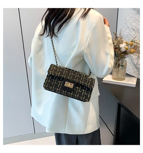 Detailansicht der gelb-schwarzen Tweed-Umhängetasche mit goldener Kette am Model
