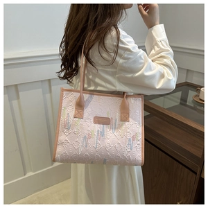 Detail of light pink tote bag featuring quilted texture and colorful embroidery accents
