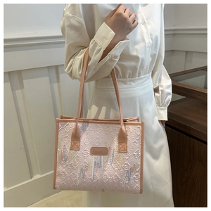 Detail of pink tote bag with geometric diamond embossing and colorful floral embroidery