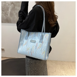 Detail view of light blue tote bag with colorful wave embroidery and texture