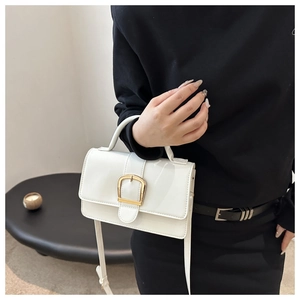 Détail du sac bandoulière blanc brillant avec boucle dorée et poignée supérieure chic