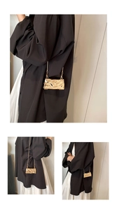 Detailansicht einer goldenen Muschel-Tasche mit Wellenstruktur und eleganter Metallkette