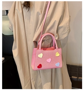 Pink textured fabric mini tote bag featuring colorful leather heart patches and crossbody strap