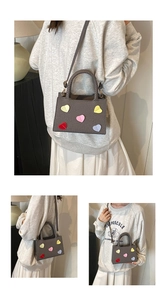 Chic grey crossbody square bag with colorful heart patches shown on a model