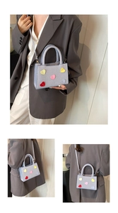 Detail view of light blue textured handbag featuring colorful heart shaped appliqués