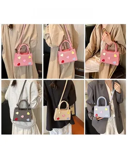 Detail showing mini tote bags with heart patches in pink, grey, beige and blue colors
