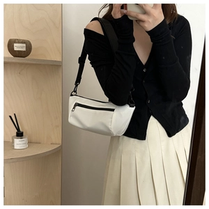Crossbody moon bag in off-white canvas with black strap styled in a casual daily outfit
