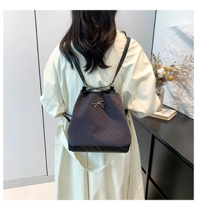 Detailed view of women's grey polka dot backpack with metallic bow and leather base