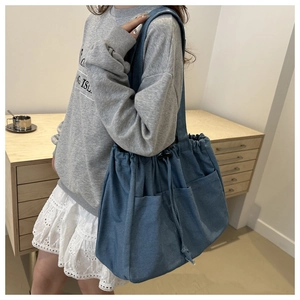 Detailed view of a blue denim tote bag with external pockets and drawstring closure