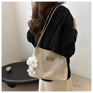 Detail of off-white woven texture shoulder bag with cloud charm and brand label