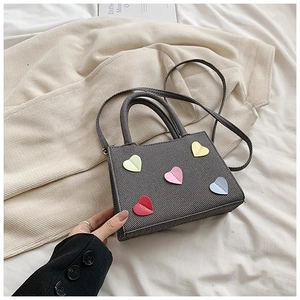 Vue macro détaillée de la texture du canevas gris et des écussons de cœur colorés sur le sac