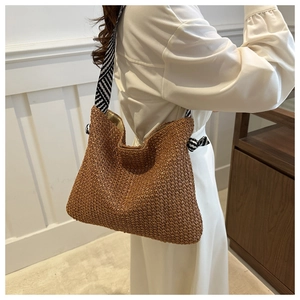 Detail einer braunen geflochtenen Strohtasche mit geometrischem schwarz-weißem Seidenband