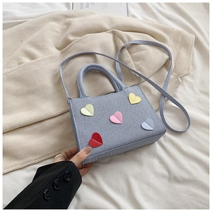 Gros plan du sac bandoulière bleu clair texturé orné de patchs colorés en forme de cœur