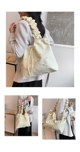 Detail view of cream shoulder bag with pleated straps and sparkling rhinestone accents