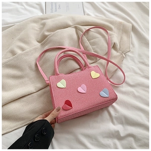 Détail du sac cabas en toile rose avec écussons cœurs 3D et anses tissées assorties