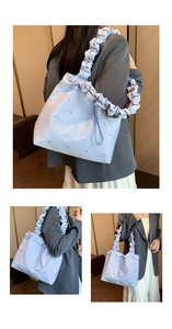 Close-up of light blue ruched shoulder bag featuring silky fabric and metal rivet details