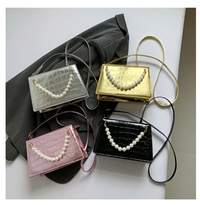 Flat lay of crocodile pattern party bags in four colors with pearl chain handles