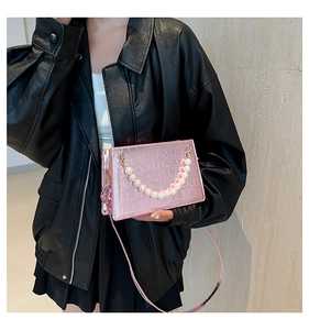Pink crocodile-embossed handbag featuring elegant large pearl handle and slim shoulder strap
