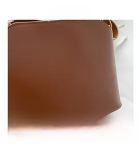 Close-up of brown matte leather handbag with gold metal hardware and fine stitching