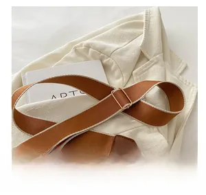 Detail of adjustable wide woven shoulder strap with gold metal buckle on brown tote