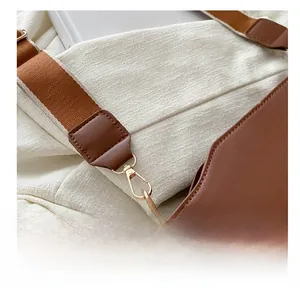 Detailed macro view of the gold-tone metal hook and striped woven shoulder strap