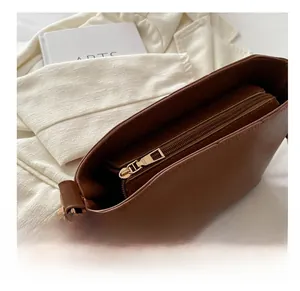 Close-up of smooth gold zipper and spacious multi-compartment interior of brown leather bag