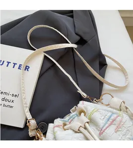 Detail of cream bucket bag with colorful wavy embroidery on textured fabric and gold buckle