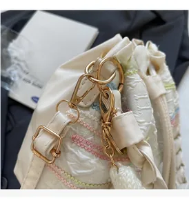 Detail of cream bucket bag showing gold metal buckle and colored wavy stitching