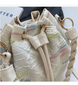 Detailed close-up of rainbow wave embroidery and drawstring closure on bucket bag