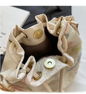 Detail of embroidered wavy pattern bucket bag with leather trim and magnetic closure