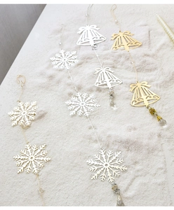 Close-up of metallic snowflake and bell ornaments with bead drops for Christmas decor