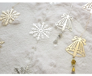 Close-up of metal snowflake and bell ornaments with beads on snowy background