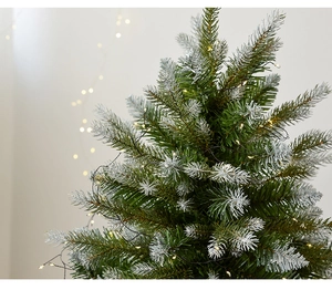 Macro detail of lush 60cm Christmas tree needles with snow flocking and warm LED lights