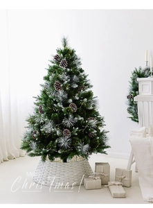 Detail of frosted Christmas tree with natural pinecones, warm LED lights, and wicker base