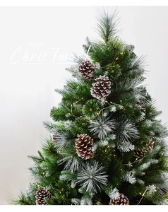 Detail of frosted Christmas tree with natural pine cones and warm glowing LED lights