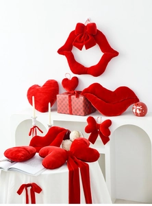 Close-up of red velvet heart, lip, and bow cushions for romantic festive decoration