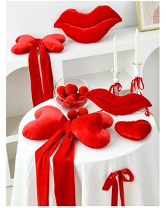 Detail of red plush heart pillow and lip-shaped velvet cushions on a white table