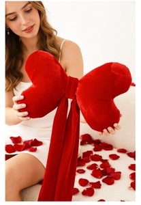 Detail of a large red velvet bow pillow held by a model in a romantic setting