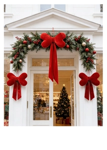 Red velvet Christmas bows hanging on a white door frame with festive greenery and pine cones