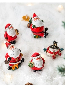 Close-up of miniature resin Santa Claus and snowman figurines on artificial snow