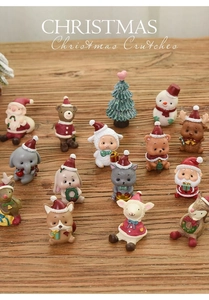Flat lay of resin Christmas miniatures like Santa and reindeer on a wooden table