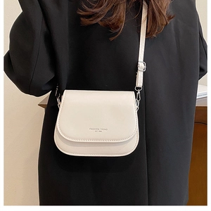 Detail of off-white leather saddle bag with Fashion Trend text on black coat background